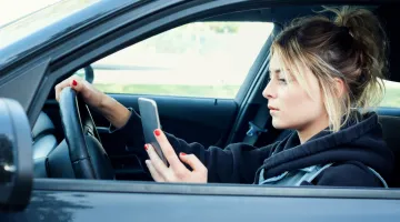 Teen driver looking at phone while driving a car